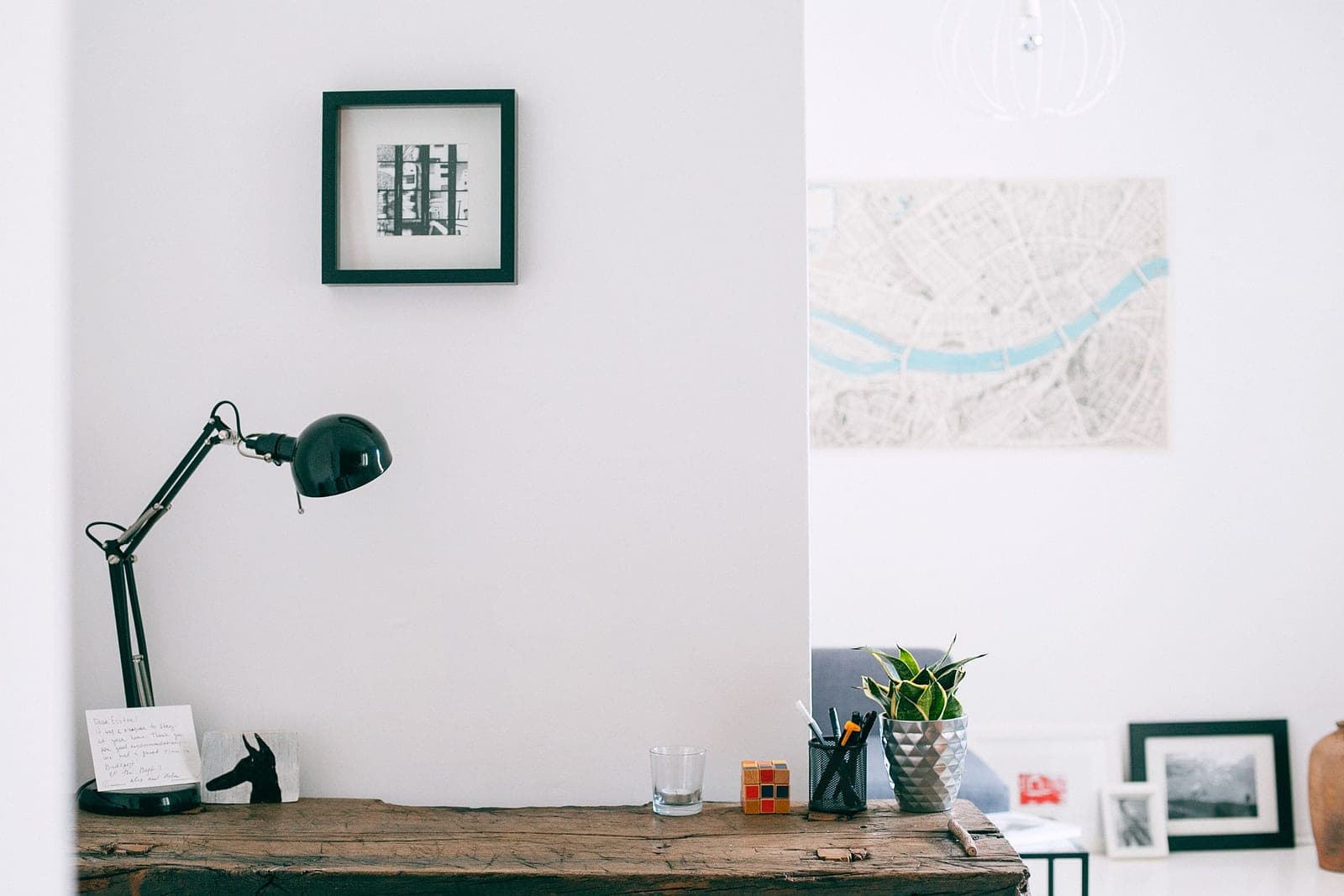 A desk lamp beside a small potted plant in a bright room
